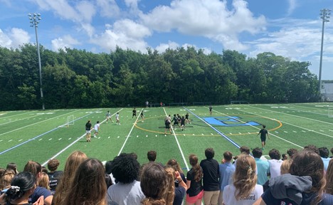 Students watch the seniors (in black) play the freshmen on the field in the Freshmen Friday soccer game.