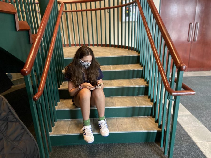 Cianna Vengoechea Schiff 25 sits on the steps of Lewis Auditorium looking solemnly at her phone.