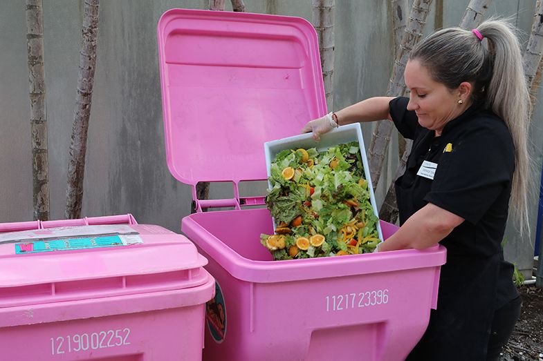 SAGE Dining Services employee Ms. Denise Diaz disposes of food waste in the new composting bins.